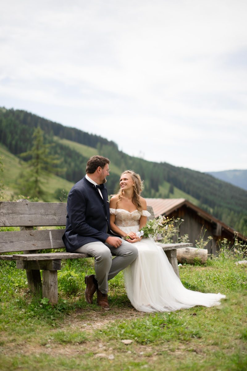 Paar bei ihrer Hochzeit auf einer Bank in den Bergen in der Natur