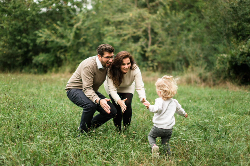 Szene im Wald einer kleinen Familie, Kind läuft auf Eltern zu