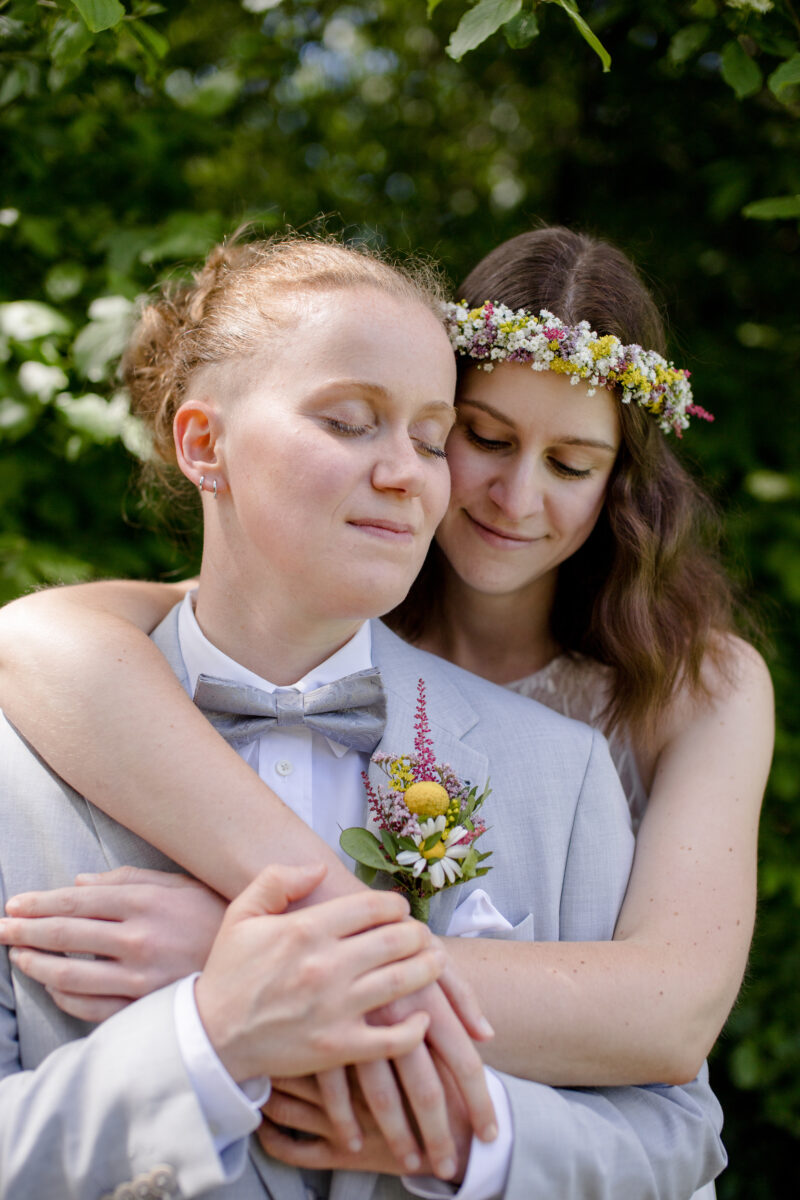 Innig umarmendes gleichgeschlechtliches Brautpaar bei ihrer Hochzeit